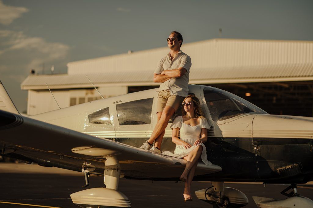 Couple sits on a plane at Bowman Field in Louisville Kentucky watching the sunset.