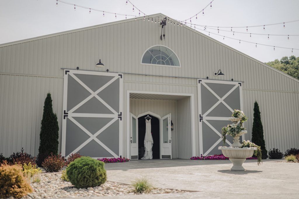 Wedding dress hangs between elegant barn doors at the Woods at Cedar Springs