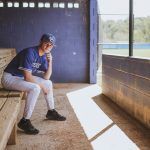 High School senior sits in the ball pen for his team for his senior photos