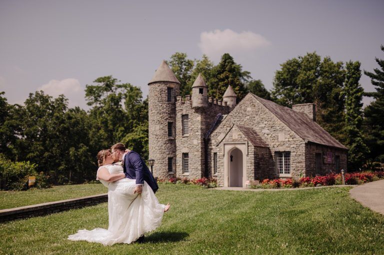 A bride and groom dip in front of the castle of Yew Dell Botanical Gardens